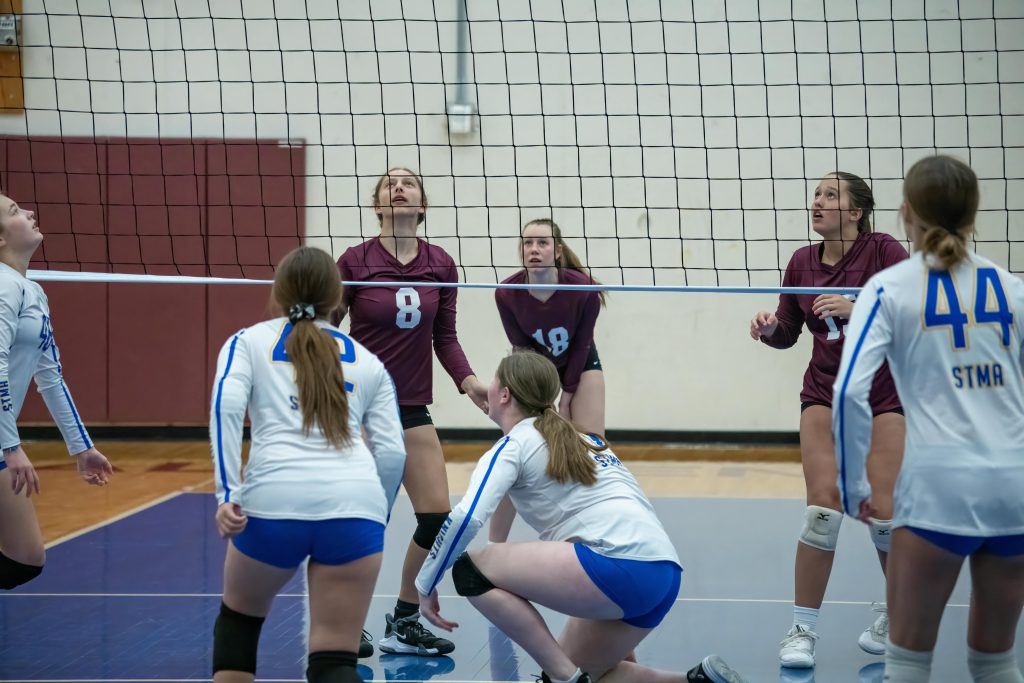 Intense volleyball match between high school teams in Rochester, MN with focused players preparing for a net play.