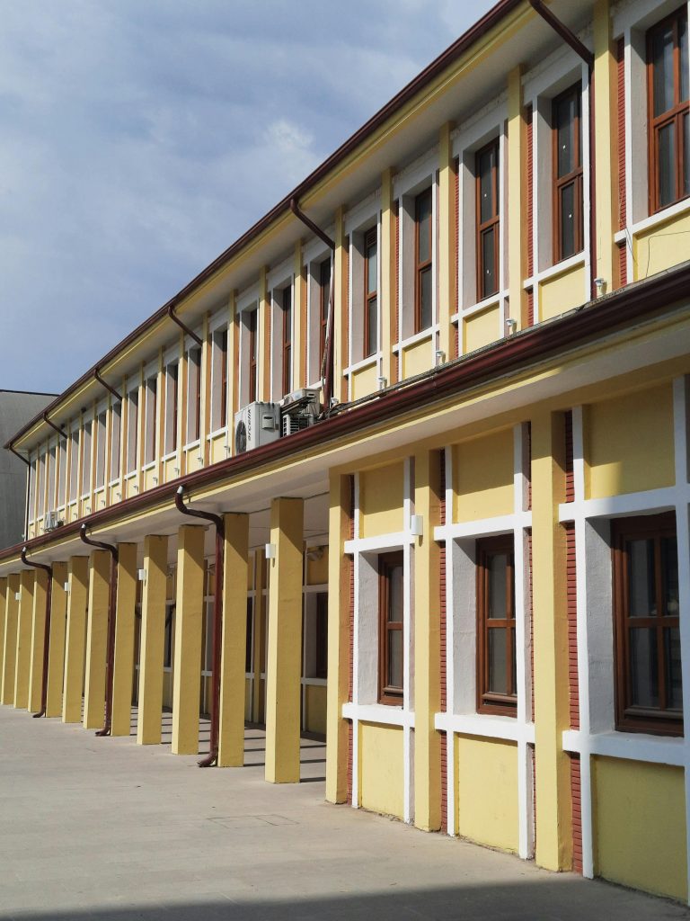 Elegant facade of a modern educational building featuring tall windows and columns on a sunny day.