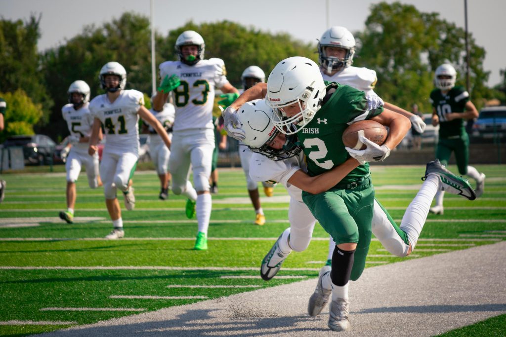 High school football players in intense action on the field during a game.