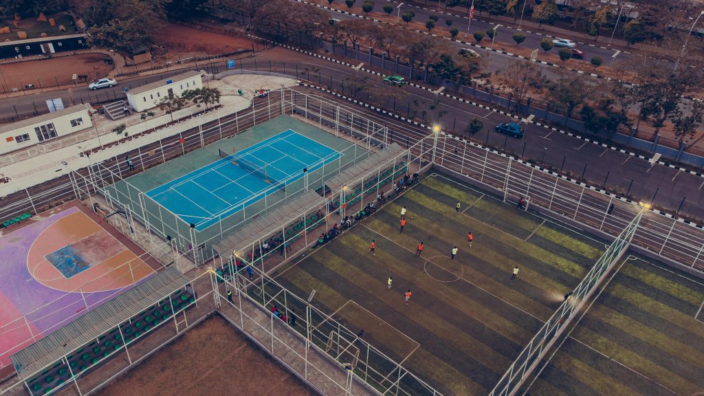 Aerial shot of a sports complex with soccer, tennis, and basketball courts during the day.