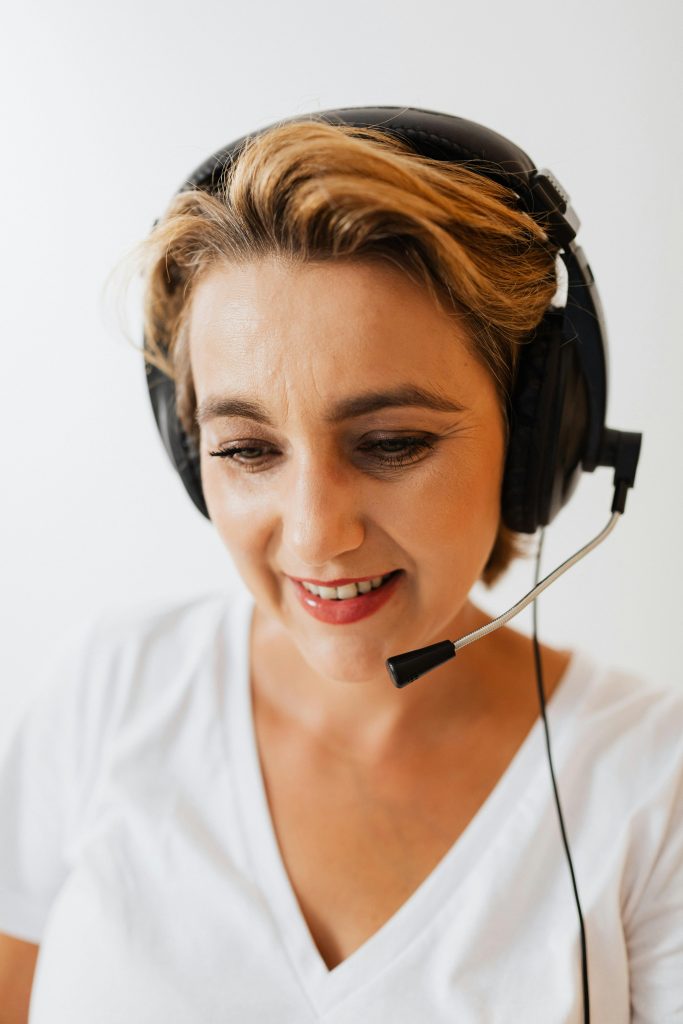 A woman wearing a headset smiles while working in customer service.